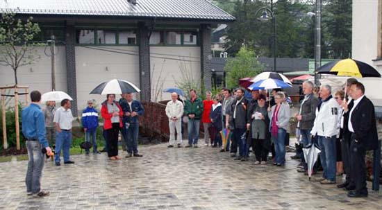 Dorfplatz mit Menschenmenge, die alle einen Regenschirm halten, da es regnet