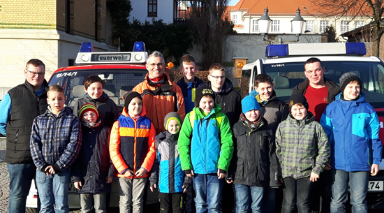 Kinder posieren vor 2 Feuerwehrfahrzeugen