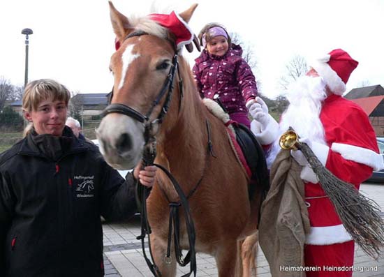 Kind reitet auf Pferd mit Weihnachtsmann nebendran
