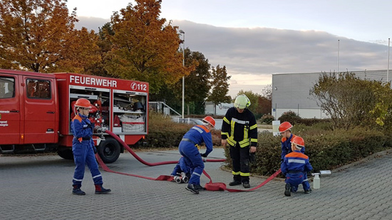 3 Kinder rollen einen Schlauch auf