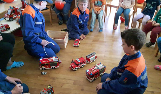 Kinder spielen am Boden mit Spielzeug Feuerwehrautos