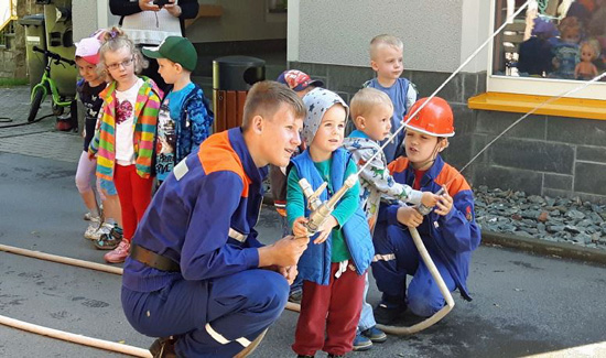 Feuerwehrkraft hilft Kind eine Angel zu halten