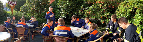 Jugendfeuerwehr sitzt an einem Tisch im Freien