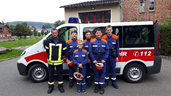Jugendfeuerwehr posiert vor einem Feuerwehrauto