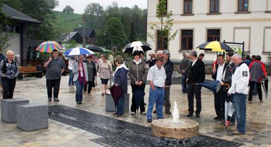 Dorfplatz mit Menschenmenge, die alle einen Regenschirm halten, da es regnet