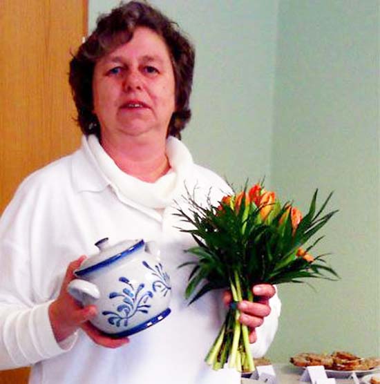 Frau hält Keramiktopf und einen Blumenstrauß in der Hand