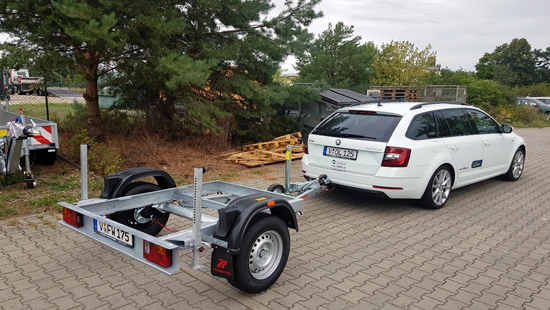 Auto mit neuem Anhänger gekoppelt steht in einer Einfahrt