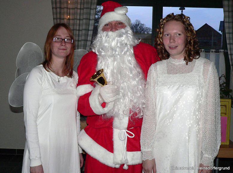 Links und rechts neben dem Weihnachtsmann steht jeweils ein Engel