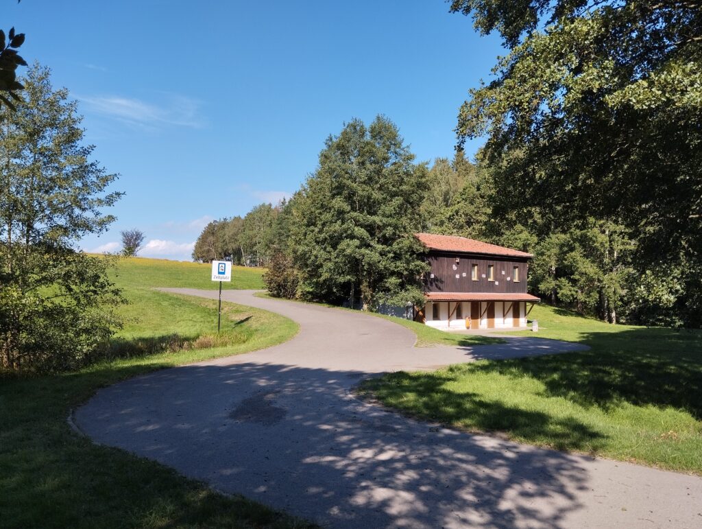 Blick auf das Campingplatzgebäude an dem ein geteerter Weg vorbeiführt