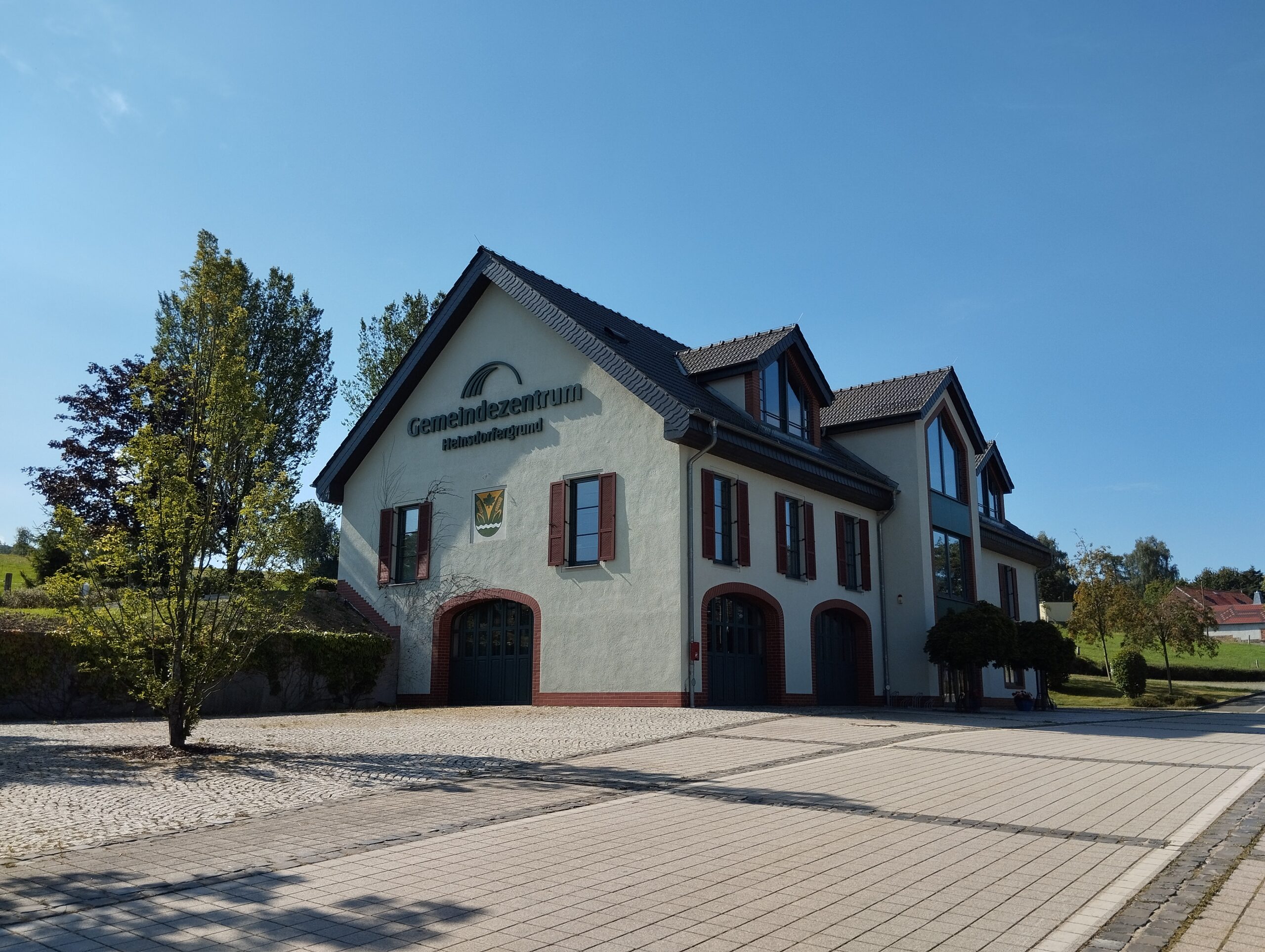 Blick aufs Gemeindezentrum mit Bäumen im Vordergrund