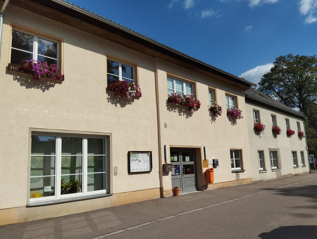 Blick auf das Gemeindeamt, beige Fassade mit Blumen an den Fenstern