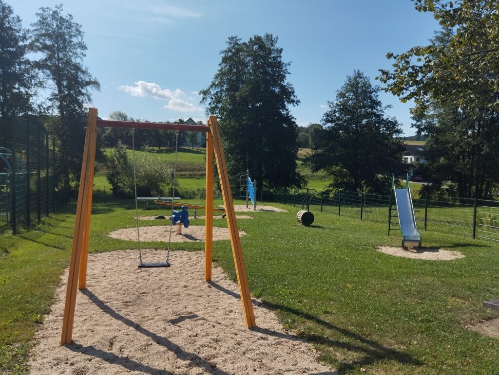 Spielplatz mit Schaukel, Sand und Wiese