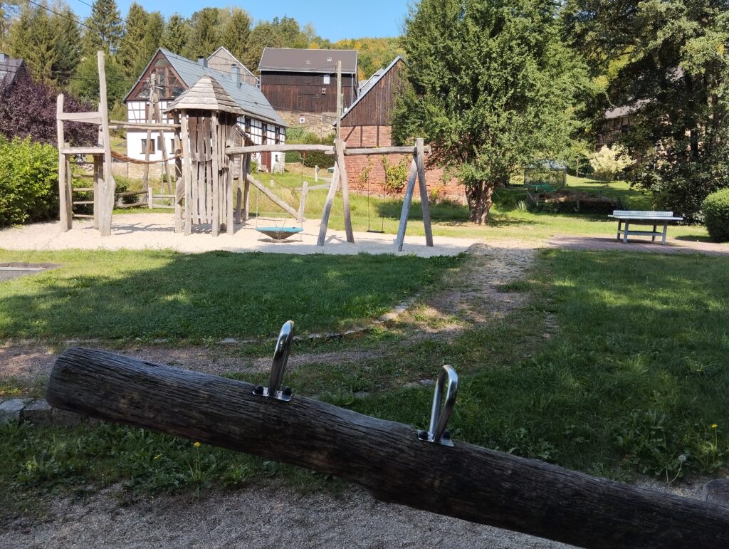 Wippschaukel auf Spielplatz mit Klettergerüst im Hintergrund