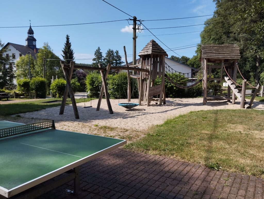 Tischtennisplatte neben Klettergerüst auf einem Spielplatz