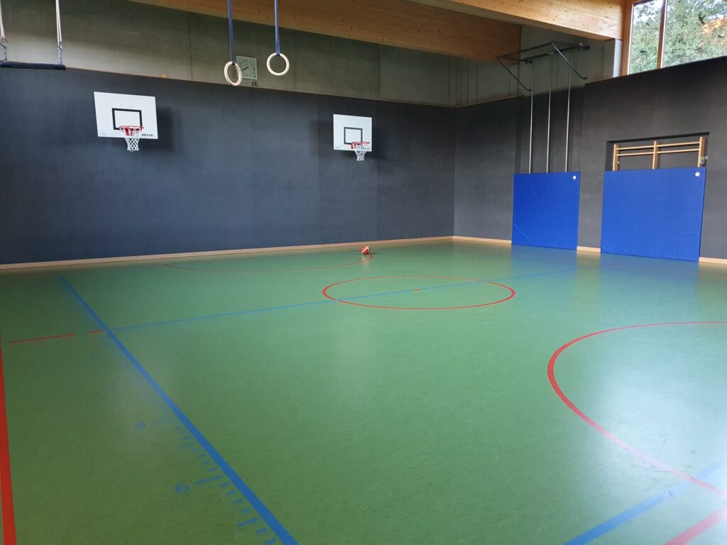 Innenansicht der Turnhalle Hauptmannsgrün mit blauen Wänden und grünem Boden