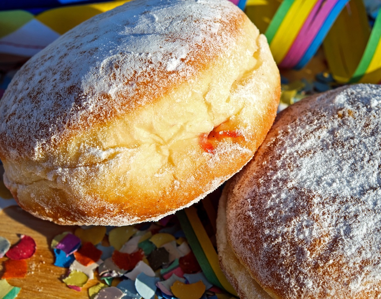 Zwei Pfannkuchen sind zu sehen, bei dem einen schaut Marmelade raus. Weiterhin sind man auf dem Bild Konfetti und Luftschlangen.