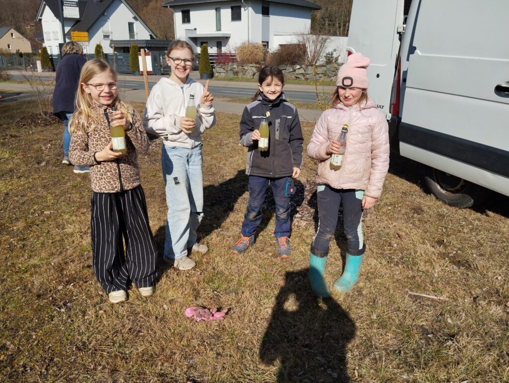 Auf dem Bild sind vier stehende Mädchen zur Pause (halten ein Getränk in der Hand) beim Arbeitseinsatz zu sehen.