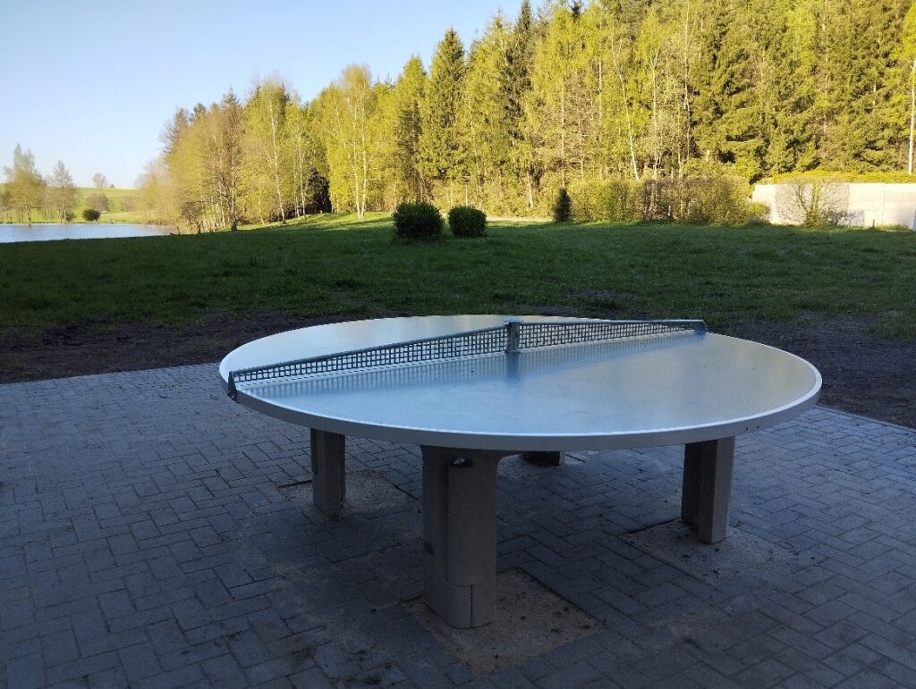Das Foto zeigt die neue runde Tischtennisplatte auf dem Gelände am Mühlteich in Hauptmannsgrün, im Hintergrund die Liegefläche und der Mühlteich